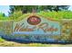 Stone entrance sign with 'Wildcat Ridge' lettering, set amidst lush greenery for a grand welcome at 6175 Puma Sands, Lone Tree, CO 80124