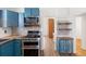 Charming kitchen with blue cabinetry, stainless steel appliances, patterned backsplash, and open shelving at 1103 Lipan St, Denver, CO 80204