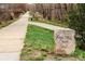 Trail surrounded by trees and greenery, marked by a stone with 