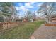 Fenced backyard with mature trees, wooden fencing and a gravel walkway at 11972 W Dakota Dr, Lakewood, CO 80228