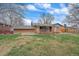 View of the backyard featuring a brick home, wooden fence, and a large grassy area at 11972 W Dakota Dr, Lakewood, CO 80228