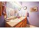 Lavender painted bathroom featuring a double sink, spacious vanity, and neutral tile flooring at 10487 W Hampden Ave # 101, Lakewood, CO 80227