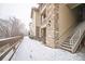 Side view of the building featuring stone accents with walkway and stairs covered in light snow at 10487 W Hampden Ave # 101, Lakewood, CO 80227