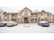 The front of the building with parking area features stone accents and multiple balconies in the winter at 10487 W Hampden Ave # 101, Lakewood, CO 80227