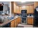 Well-lit kitchen with oak cabinets, double oven and tile flooring at 10487 W Hampden Ave # 101, Lakewood, CO 80227