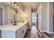 Bright bathroom featuring double sinks, quartz countertops, modern lighting, and wood-look flooring at 3344 Carabiner St, Castle Rock, CO 80108