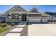 Charming two-story home featuring a welcoming front porch, gray siding, stone accents and a three car garage at 3344 Carabiner St, Castle Rock, CO 80108