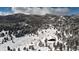 Aerial view showcasing a snow-covered landscape with a red barn and mountainous terrain at 3999 Evans Ranch Rd, Evergreen, CO 80439