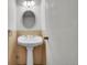 This bathroom features a pedestal sink with round mirror and bright lighting at 7995 E Mississippi Ave # C1, Denver, CO 80247