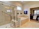 Bright bathroom with tub, frameless shower, and view into the main bedroom at 4971 Bross Pl, Broomfield, CO 80023