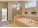 Bright bathroom with a soaking tub, glass enclosed shower, and tiled floor at 4971 Bross Pl, Broomfield, CO 80023