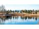 Picturesque pond with wooden pier surrounded by lush greenery, trees, and distant mountains at 4971 Bross Pl, Broomfield, CO 80023