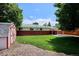 Exterior view of the home's backyard featuring green grass, a gravel area, and a storage shed at 1687 S Field Ct, Lakewood, CO 80232