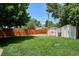 Spacious backyard featuring lush green grass, two storage sheds, and a tall wooden fence for added privacy at 1687 S Field Ct, Lakewood, CO 80232