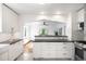 Modern kitchen featuring white cabinets, marble backsplash, stainless steel appliances and an open view to the living area at 3036 Birch St, Denver, CO 80207