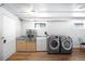 Well-lit laundry area with newer washer and dryer, cabinets and wooden floor at 3036 Birch St, Denver, CO 80207