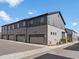 Modern gray townhome featuring attached garages under a sunny blue sky at 12843 W Nevada Pl, Lakewood, CO 80228
