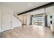 Open living room with wood floors, beamed ceilings, access to the stairway and a glass garage door to the patio at 12843 W Nevada Pl, Lakewood, CO 80228