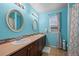 Bathroom featuring double sinks, framed mirrors, tile flooring, and blue accent walls at 6475 S Newcastle Way, Aurora, CO 80016