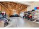 Spacious garage with high ceilings and storage shelves, with exposed wood beams, and plenty of room for vehicles at 6475 S Newcastle Way, Aurora, CO 80016