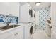 Well-lit laundry room with stackable washer and dryer, sink, and patterned wallpaper at 17 Polo Club Dr, Denver, CO 80209