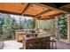 Covered outdoor kitchen with a built-in stone barbecue, seating, and a wood ceiling with recessed lighting at 17 Polo Club Dr, Denver, CO 80209