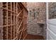 Rustic wine cellar featuring stone walls, brick flooring, and custom wood racking at 17 Polo Club Dr, Denver, CO 80209