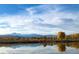 Still lake reflecting a blue sky with puffy clouds, and colorful autumn trees along the shoreline at 301 Widgeon Ln, Longmont, CO 80503