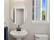 Modern half bath features sleek fixtures, pedestal sink, an oval mirror, and a window with natural light at 104 Willowick Cir, Highlands Ranch, CO 80129