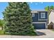Attractive two-story home with blue siding, white trim, and a two-car garage, partially obscured by a mature evergreen at 104 Willowick Cir, Highlands Ranch, CO 80129