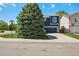 Attractive two-story home with blue siding, white trim, and a two-car garage, partially obscured by a mature evergreen at 104 Willowick Cir, Highlands Ranch, CO 80129