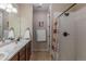 Well-lit bathroom showcasing double sinks with marble countertops and a shower with white tiled walls at 915 N Waterloo Ct, Aurora, CO 80018