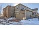 Rear view of two-story home with attached garage and snow-covered ground at 9308 Inca Dove Cir, Littleton, CO 80125