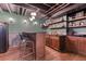 Basement bar area with dark wood cabinets, bar seating, open shelving, and stone accent wall for a cozy feel at 13830 Silverton Dr, Broomfield, CO 80020