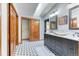 Bright bathroom with double sinks, marble countertop, wood closet doors, and stunning mosaic-patterned tile flooring at 13830 Silverton Dr, Broomfield, CO 80020