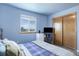 Light blue bedroom with wood-look floors, large window, sliding closet, and mini fridge at 10510 Inspiration Dr, Parker, CO 80138