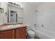 This bathroom features neutral tile, oak vanity, and shower over tub at 1280 Sable Blvd, Aurora, CO 80011