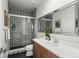 Modern bathroom with patterned tile shower, wood vanity, white countertop, and decorative mirror at 9391 E 59Th North Pl, Denver, CO 80238