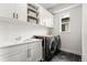 Modern laundry room features a front-load washer and dryer, white cabinets, and a white countertop with a sink at 9391 E 59Th North Pl, Denver, CO 80238