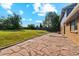 Spacious backyard with brick patio, green grass, wooden fence, and mature trees at 4522 S Robb St, Littleton, CO 80127