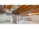 Unfinished basement featuring exposed wood beams, concrete walls, washer, dryer, and utility sink at 4522 S Robb St, Littleton, CO 80127