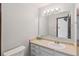 Bathroom with an oval sink, drawers, a large mirror with lights, and a toilet at 4522 S Robb St, Littleton, CO 80127