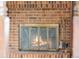 Close-up of a brick fireplace with a decorative metal screen and fireplace tools at 4522 S Robb St, Littleton, CO 80127