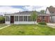 A well-kept lawn leads up to a sunroom addition on this brick home at 4453 Fillmore St, Denver, CO 80216
