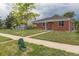 View of brick home, sidewalk, and young tree in yard with cloudy skies overhead at 4453 Fillmore St, Denver, CO 80216