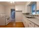 White kitchen cabinets and appliances with original wooden floors, plus sink with chrome faucet at 4453 Fillmore St, Denver, CO 80216