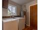 The well-lit laundry room includes a window, washer, dryer, and a water heater at 4453 Fillmore St, Denver, CO 80216