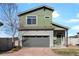 Charming two-story home featuring a green facade, gray garage door, and well-maintained front yard at 19055 E 55Th Ave, Denver, CO 80249