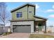 Charming two-story home featuring a green facade, gray garage door, and well-maintained front yard at 19055 E 55Th Ave, Denver, CO 80249