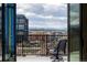 Balcony with chairs offering views of buildings and distant mountains under a partly cloudy sky at 3198 Blake St # 502, Denver, CO 80205